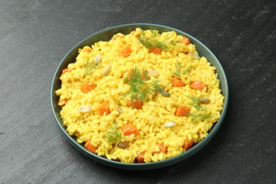 Photo of Delicious pumpkin risotto in bowl on black table, closeup