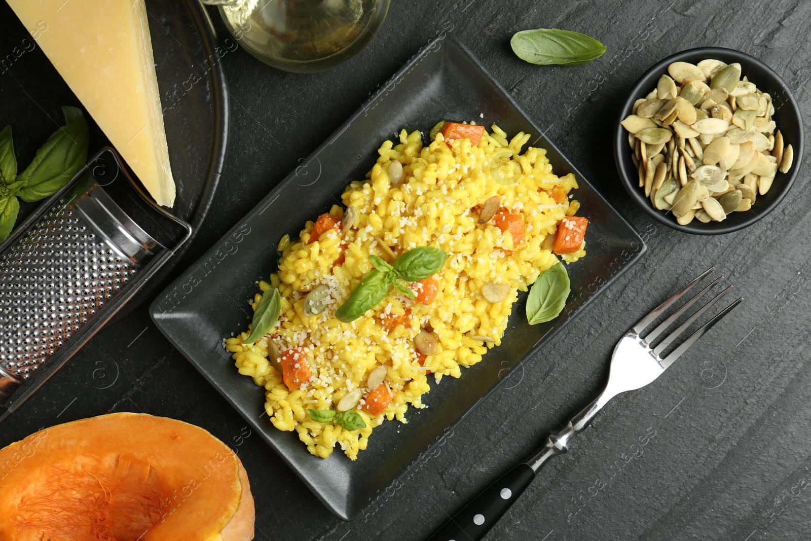 Photo of Delicious pumpkin risotto served on black table, flat lay