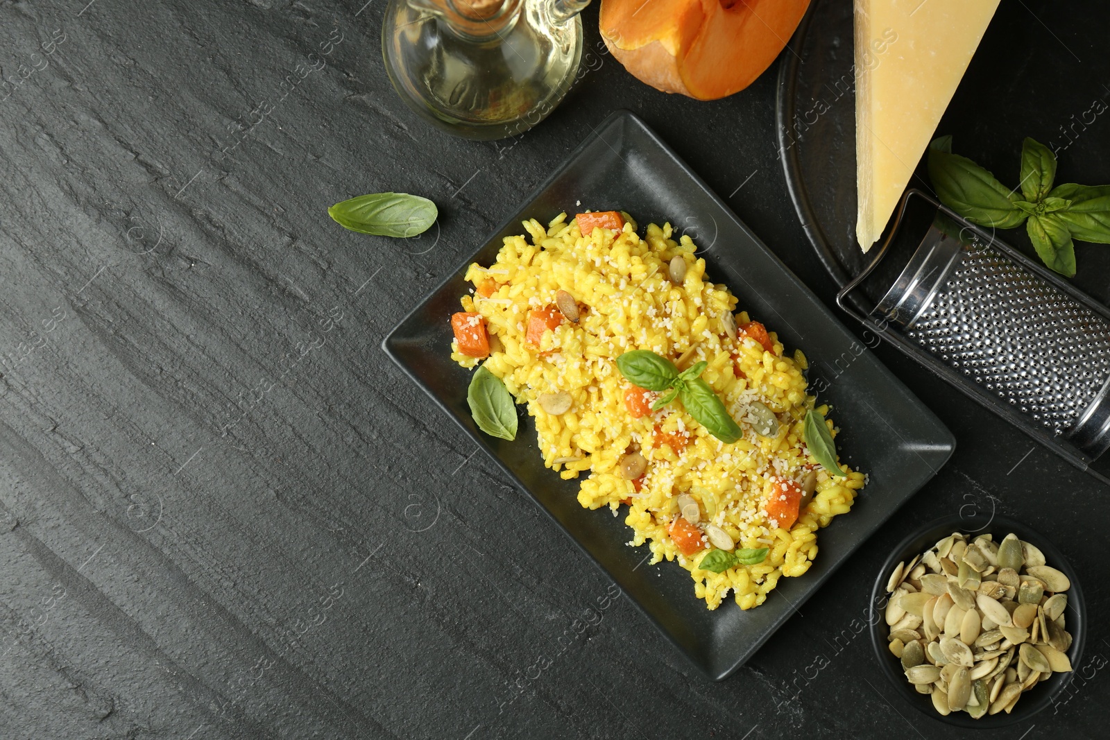 Photo of Delicious pumpkin risotto served on black table, flat lay. Space for text