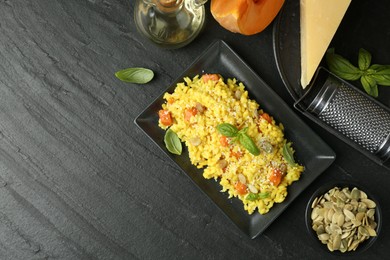 Photo of Delicious pumpkin risotto served on black table, flat lay. Space for text