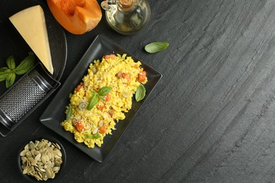 Photo of Delicious pumpkin risotto served on black table, flat lay. Space for text