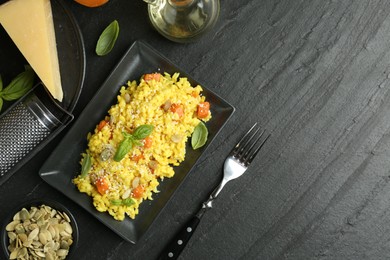 Photo of Delicious pumpkin risotto served on black table, flat lay. Space for text