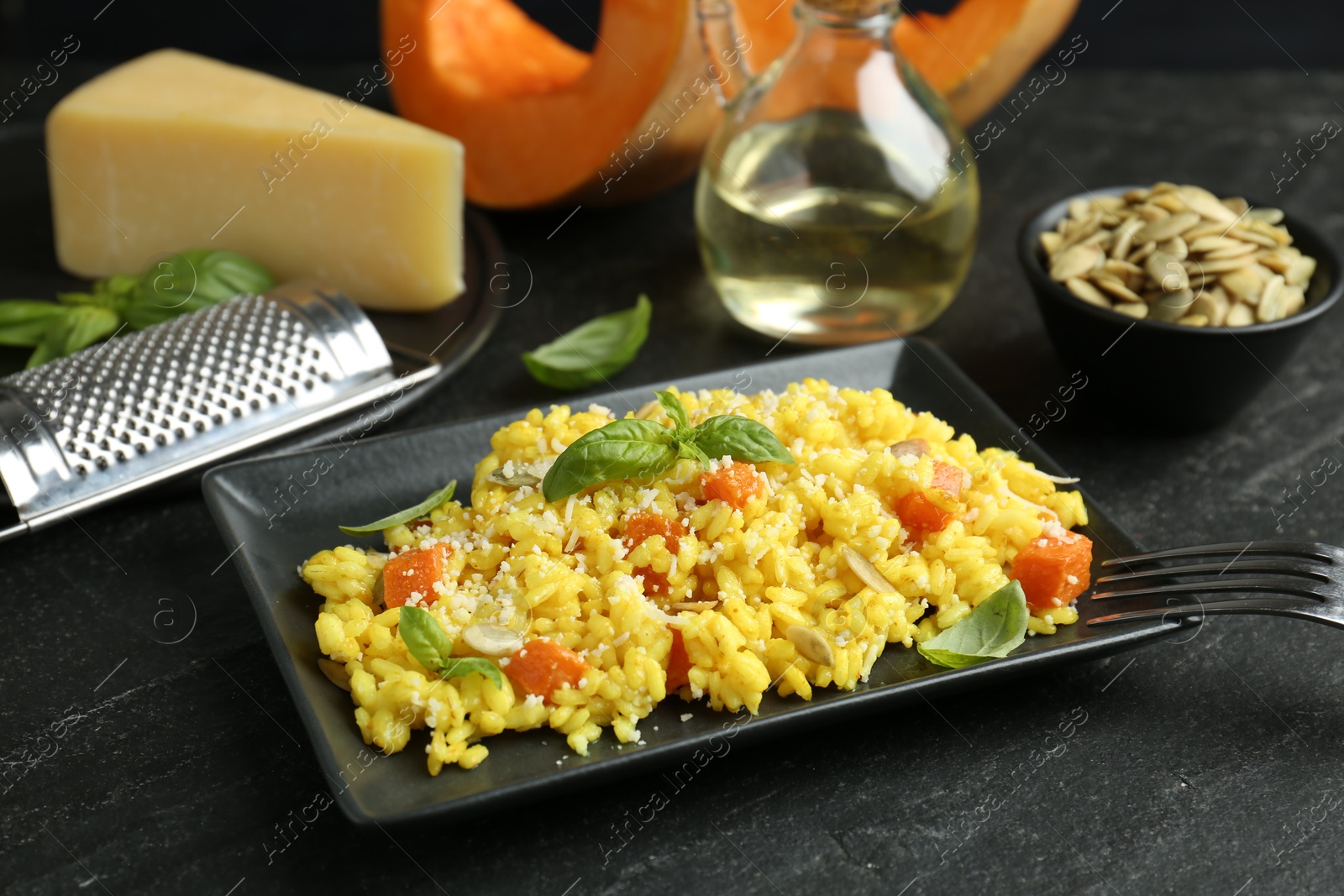 Photo of Delicious pumpkin risotto served on black table, closeup