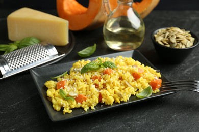 Photo of Delicious pumpkin risotto served on black table, closeup