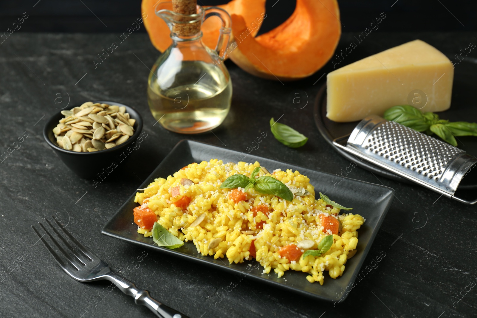 Photo of Delicious pumpkin risotto served on black table