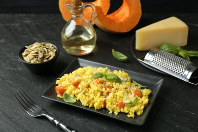 Photo of Delicious pumpkin risotto served on black table