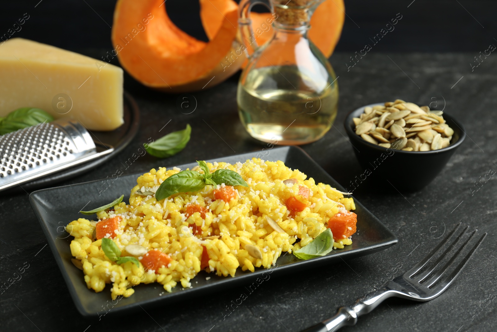 Photo of Delicious pumpkin risotto served on black table, closeup