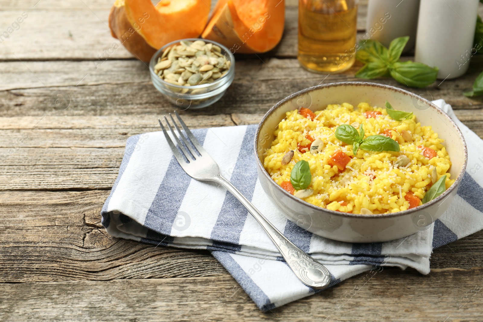 Photo of Delicious pumpkin risotto served on wooden table. Space for text