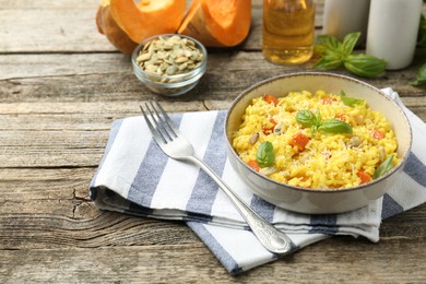 Photo of Delicious pumpkin risotto served on wooden table. Space for text