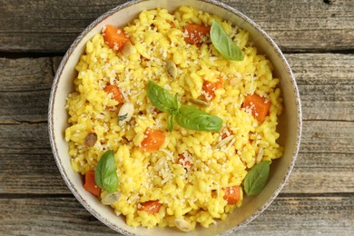 Photo of Delicious pumpkin risotto in bowl on wooden table, top view