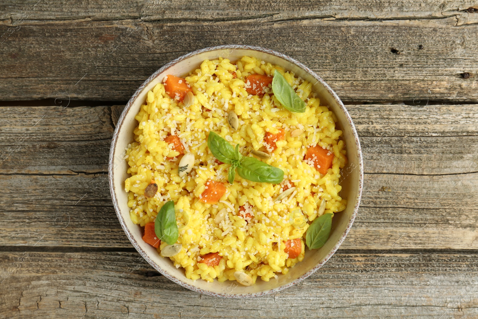 Photo of Delicious pumpkin risotto in bowl on wooden table, top view