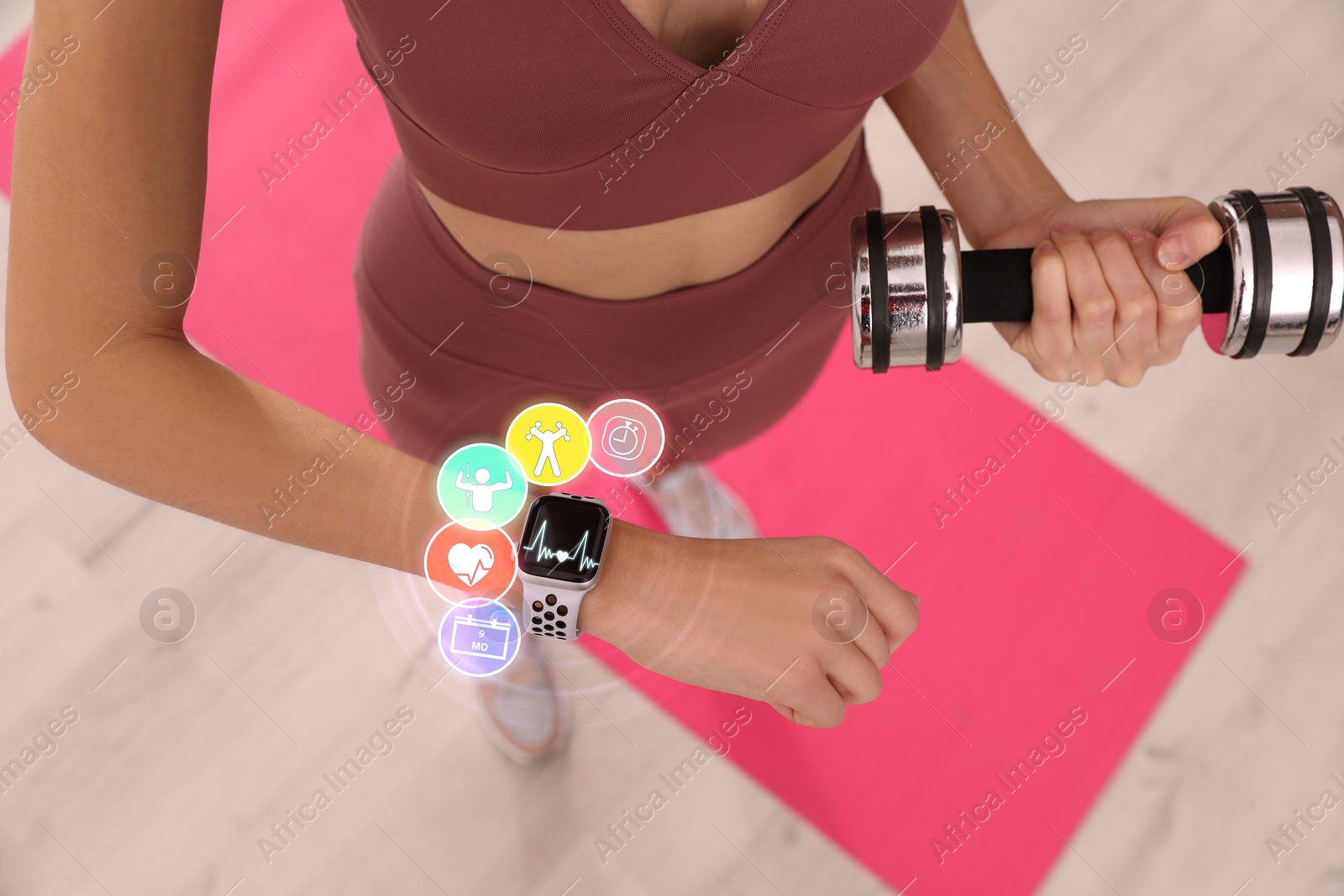 Image of Young woman using smart watch during training indoors, above view. Icons near device