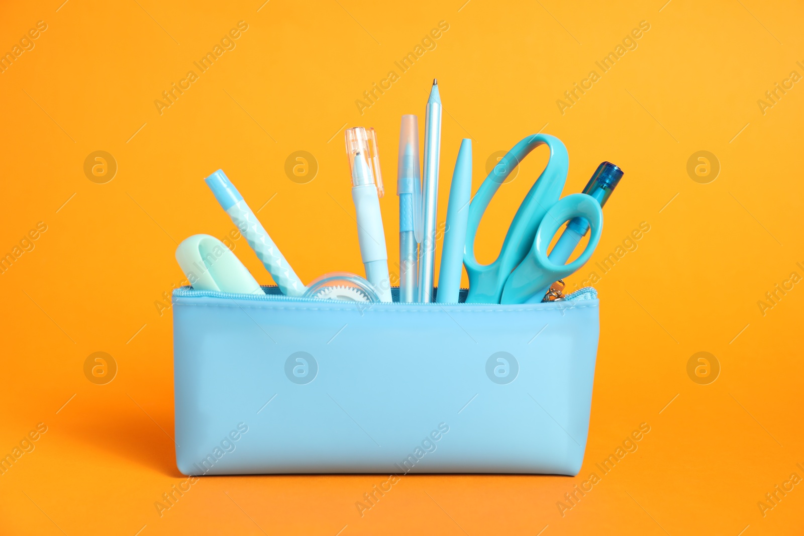 Different stationery in pencil case on orange background Photo of Different stationery in pencil case on orange background
