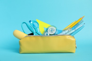 Photo of Different stationery in pencil case on light blue background