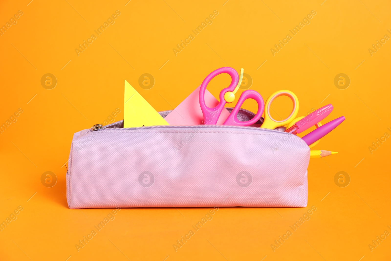 Different stationery in pencil case on orange background Photo of Different stationery in pencil case on orange background