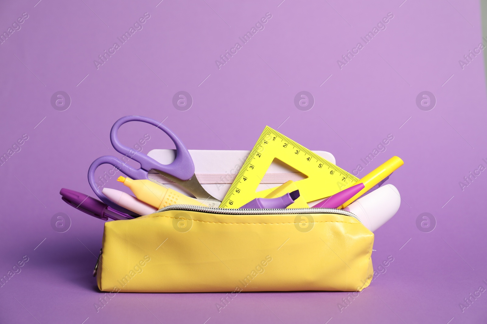 Photo of Different stationery in pencil case on purple background