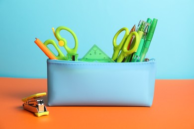 Photo of Pencil case with different stationery on color background