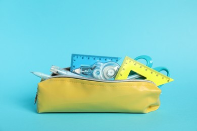 Photo of Different stationery in pencil case on light blue background