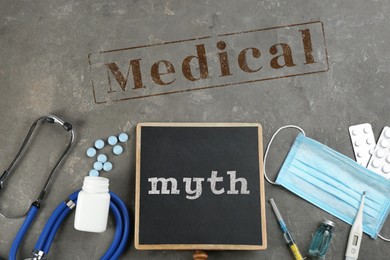 Image of Medical myth. Chalkboard, stethoscope and medicines on grey stone background, flat lay