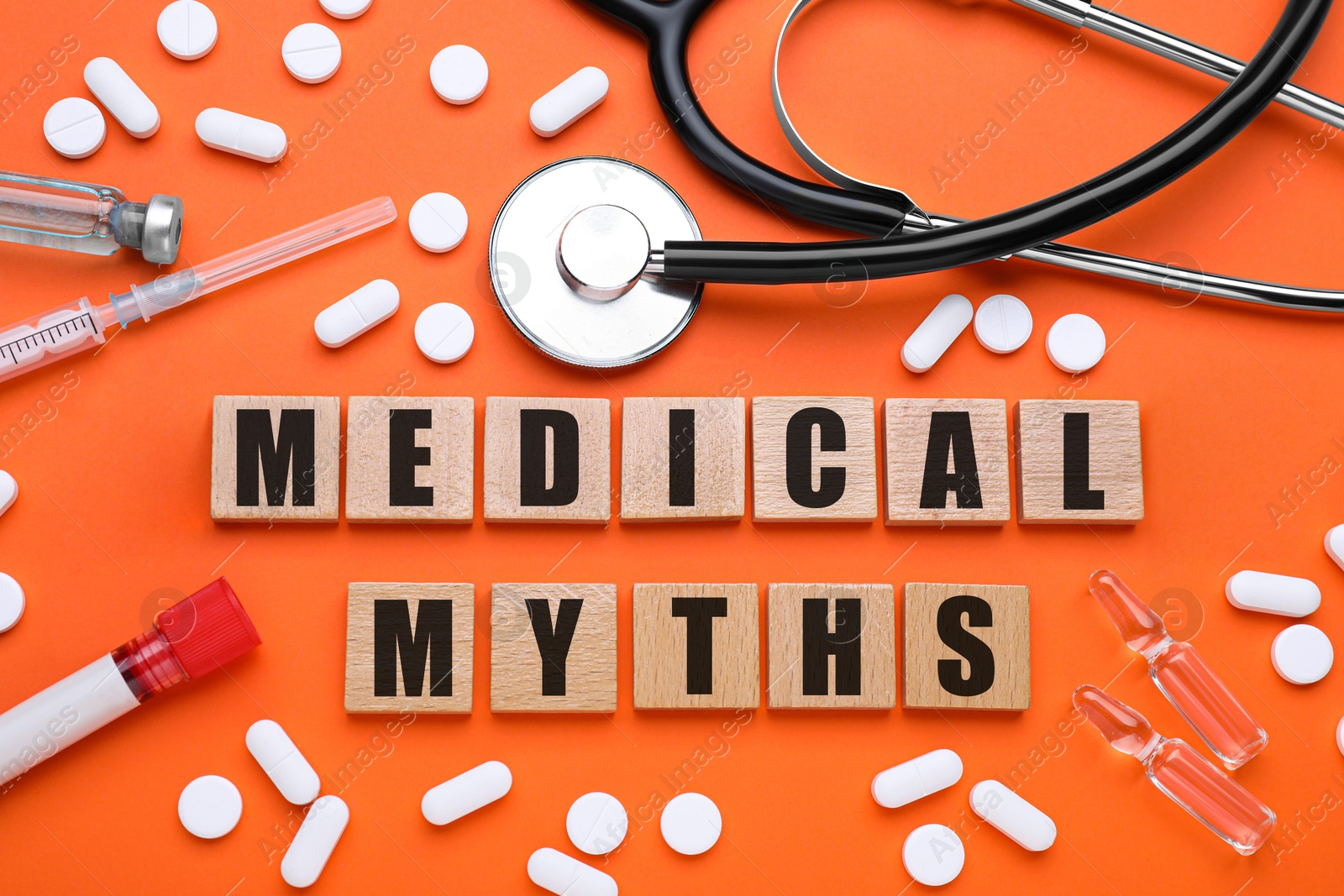 Image of Medical myths. Flat lay composition with wooden squares and medical supplies on dark orange background