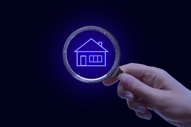 Image of Search for housing. Woman holding magnifying glass with building icon on black background, closeup