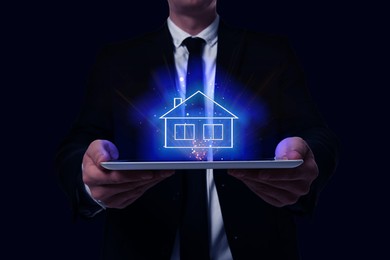 Image of Search for housing. Real estate agent holding tablet computer on black background, closeup. Illustration of house over device