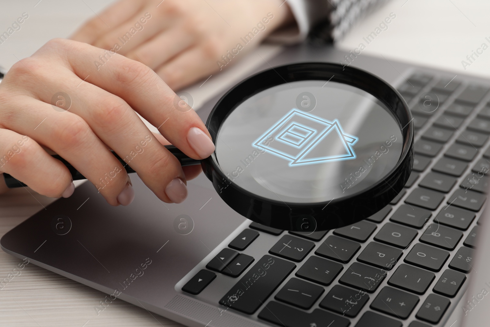 Image of Search for housing. Real estate agent holding magnifying glass with building icon over laptop, closeup