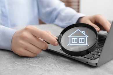 Image of Search for housing. Real estate agent holding magnifying glass with building icon over laptop, closeup