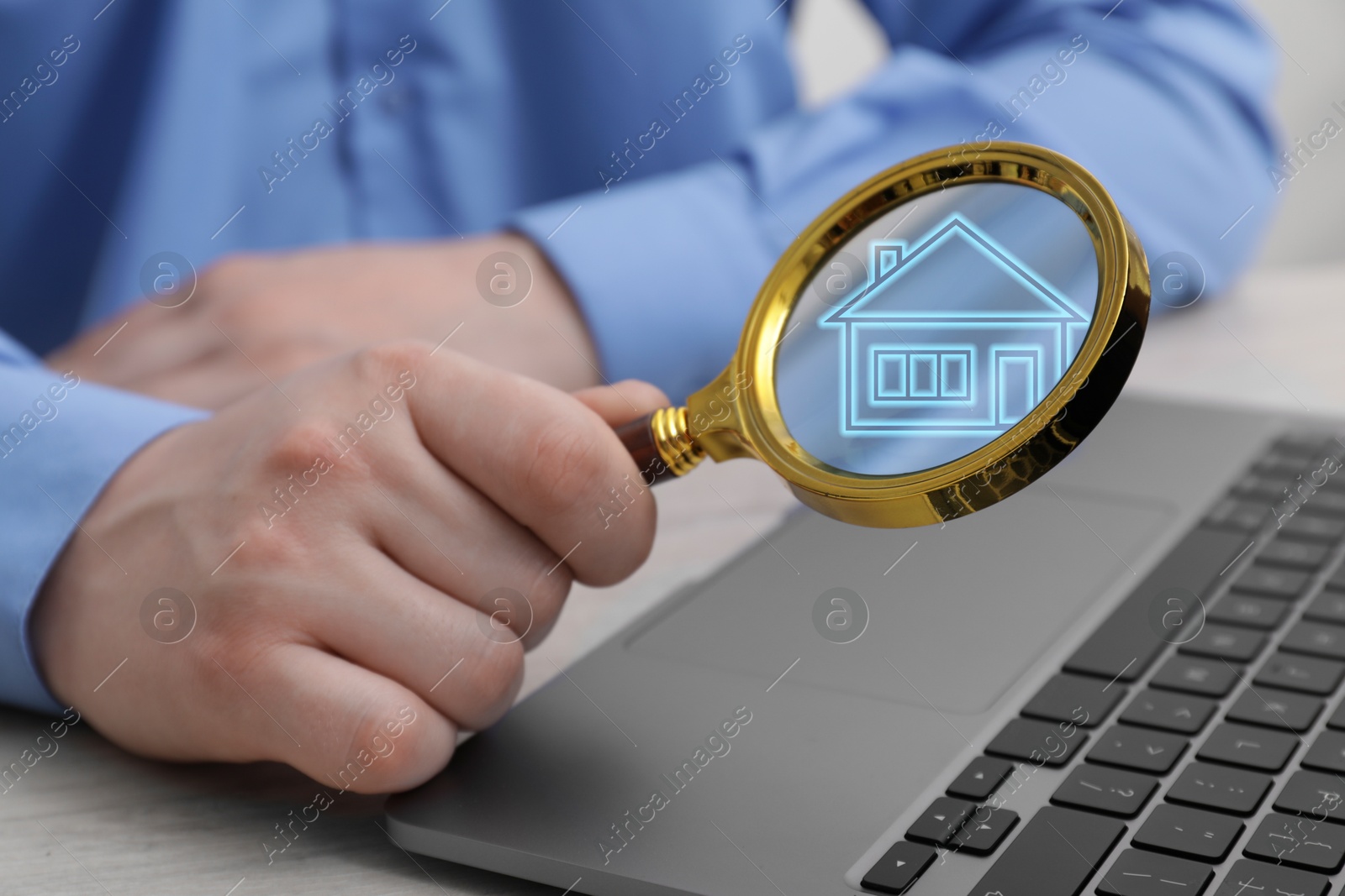 Image of Search for housing. Real estate agent holding magnifying glass with building icon over laptop, closeup