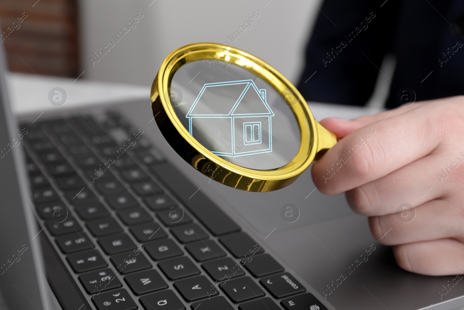 Image of Search for housing. Real estate agent holding magnifying glass with building icon over laptop, closeup