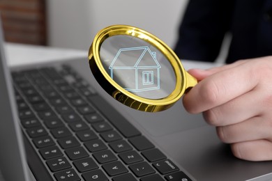 Image of Search for housing. Real estate agent holding magnifying glass with building icon over laptop, closeup