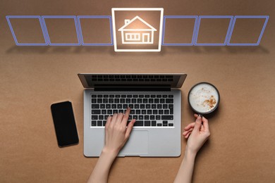 Search for housing. Woman using laptop at wooden table, top view. Virtual screen with illustration of house