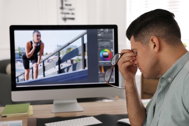 Tired retoucher at workplace with computer in office