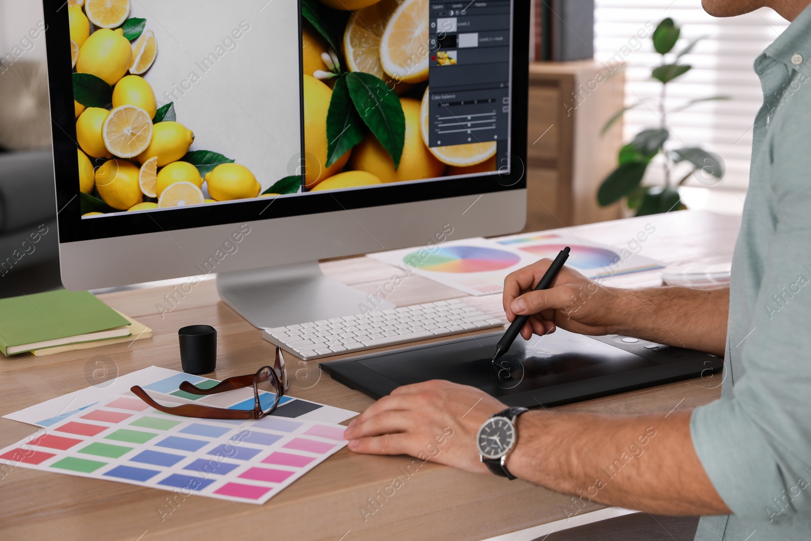 Photo of Professional retoucher working on graphic tablet in office, closeup