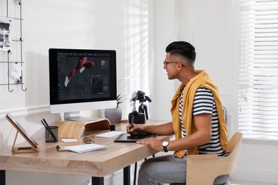 Professional retoucher working on graphic tablet at desk in office