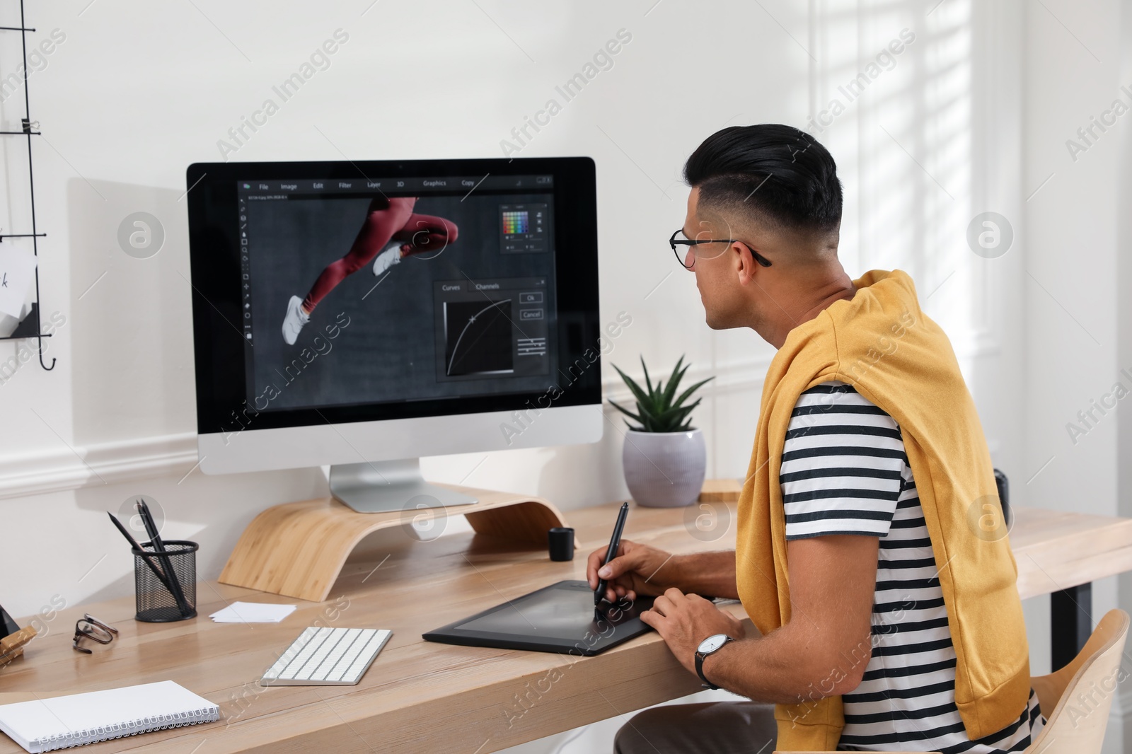 Photo of Professional retoucher working on graphic tablet at desk in office