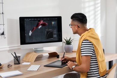 Professional retoucher working on graphic tablet at desk in office