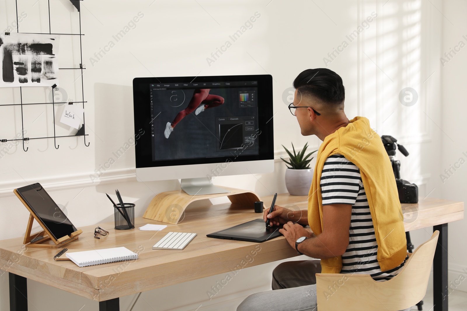 Photo of Professional retoucher working on graphic tablet at desk in office