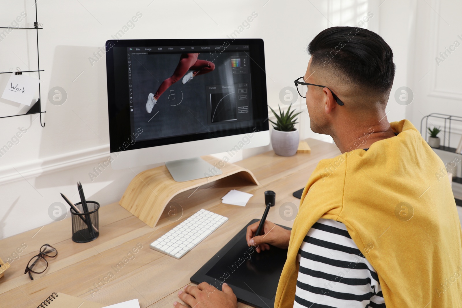 Photo of Professional retoucher working on graphic tablet at desk in office