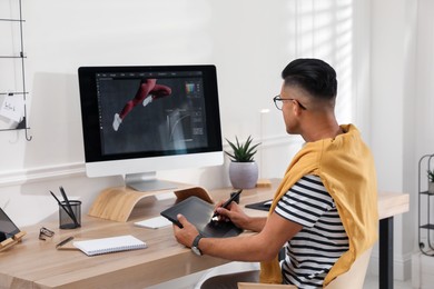 Professional retoucher working on graphic tablet at desk in office