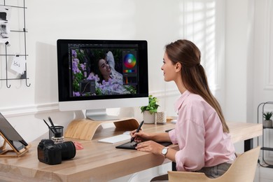 Photo of Professional retoucher working on graphic tablet at desk in office