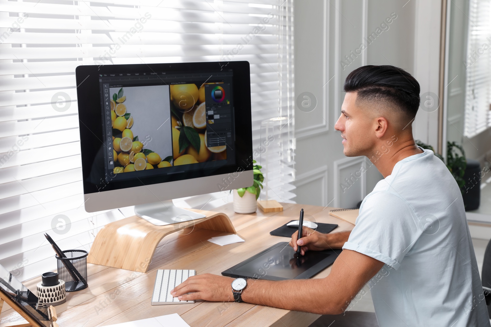 Photo of Professional retoucher working on graphic tablet at desk in office