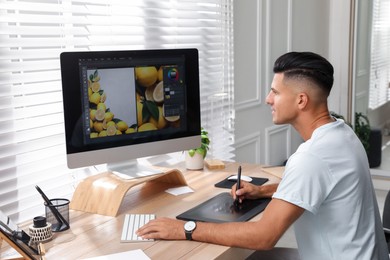 Professional retoucher working on graphic tablet at desk in office