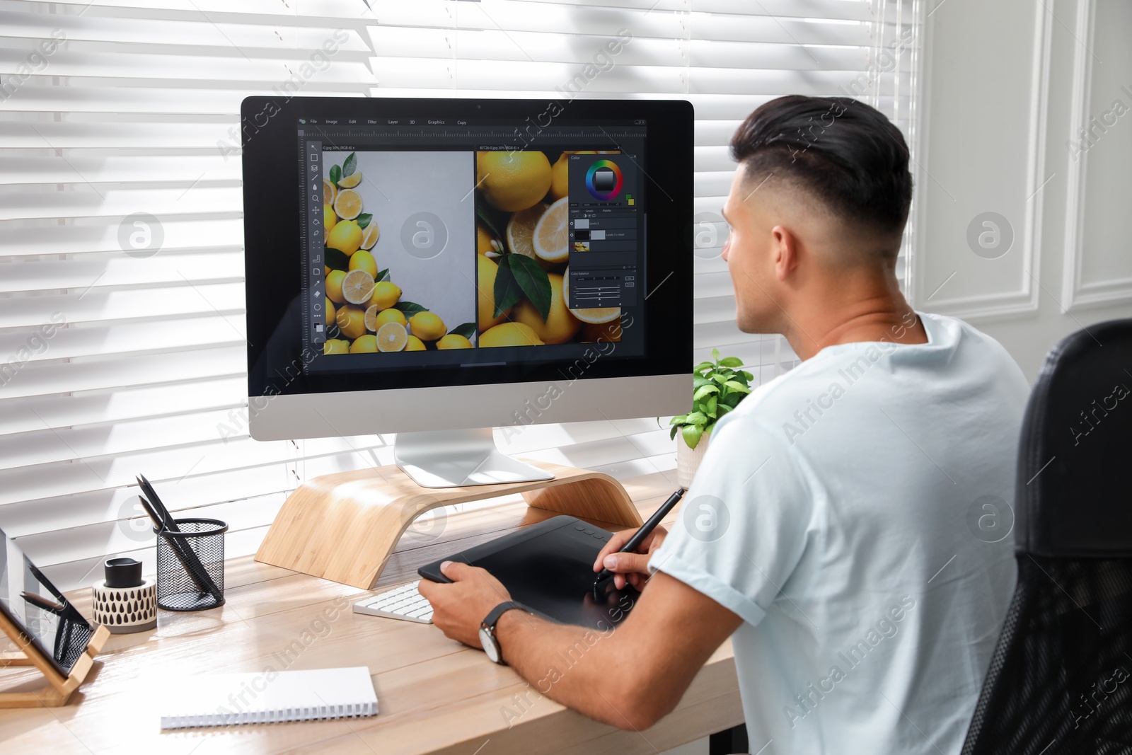 Photo of Professional retoucher working on graphic tablet at desk in office