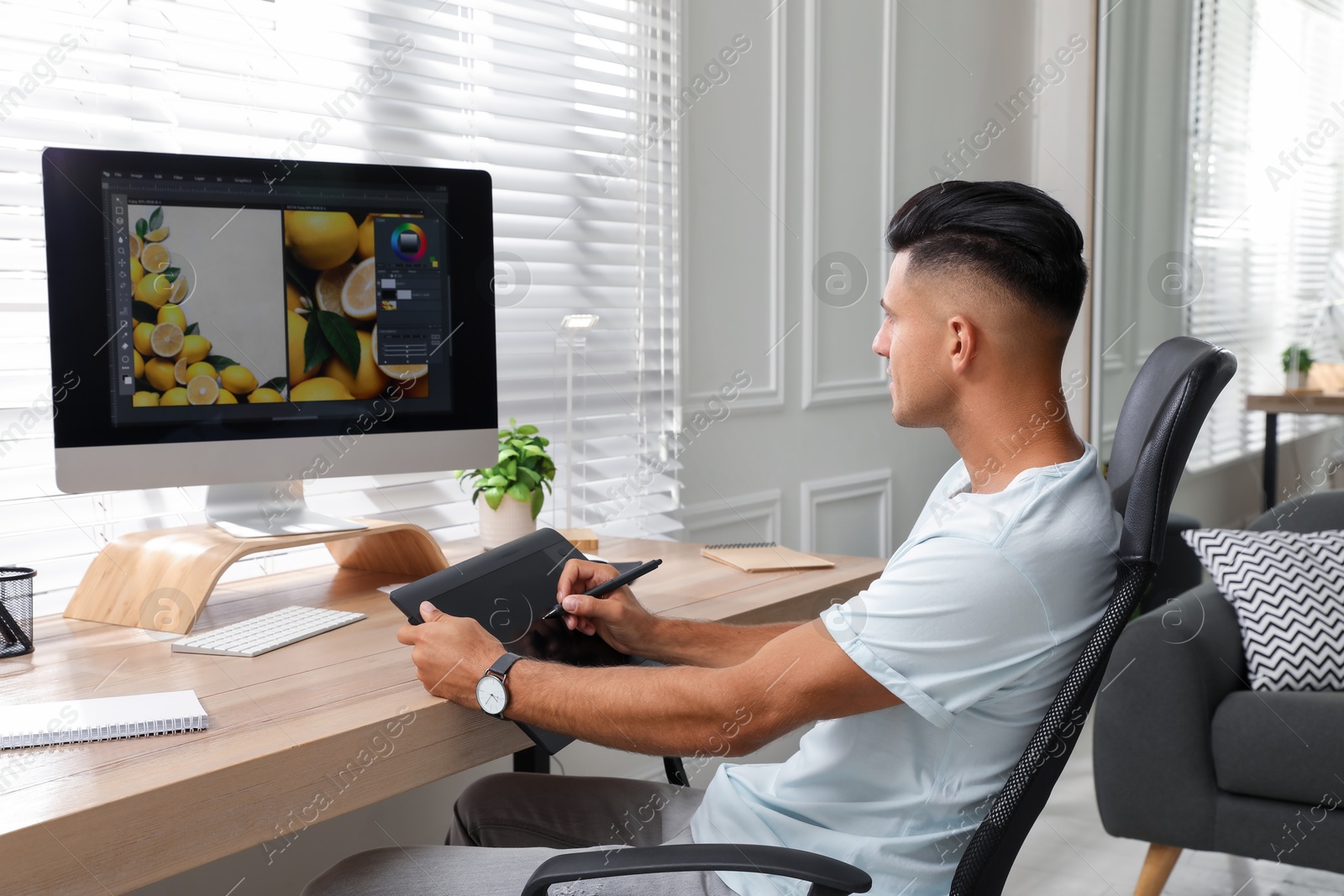 Photo of Professional retoucher working on graphic tablet at desk in office