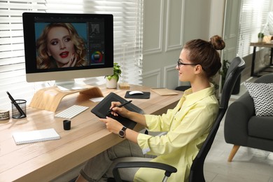 Professional retoucher working on graphic tablet at desk in office