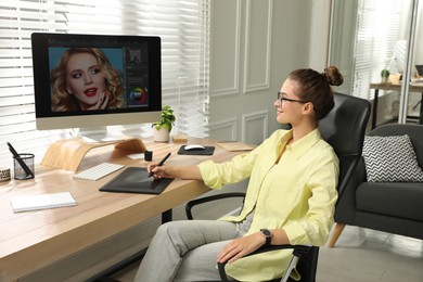 Professional retoucher working on graphic tablet at desk in office