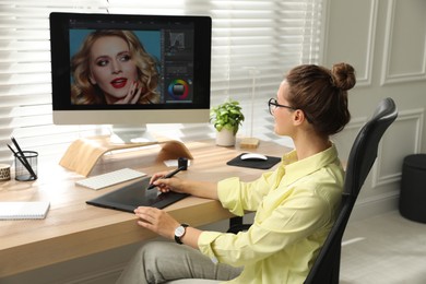 Professional retoucher working on graphic tablet at desk in office