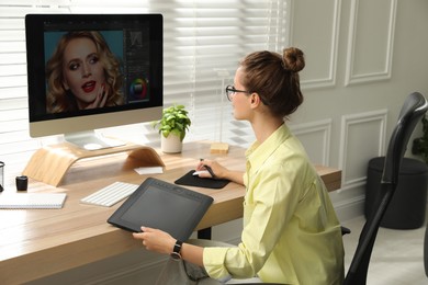 Photo of Professional retoucher working on graphic tablet at desk in office