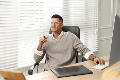 Professional retoucher working on graphic tablet at desk in office